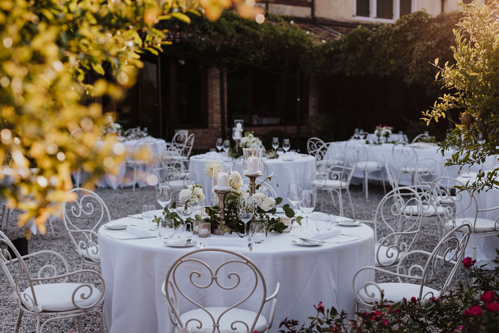 La mise en place e le decorazioni floreali di un tavolo per un matrimonio in un giardino a Venezia